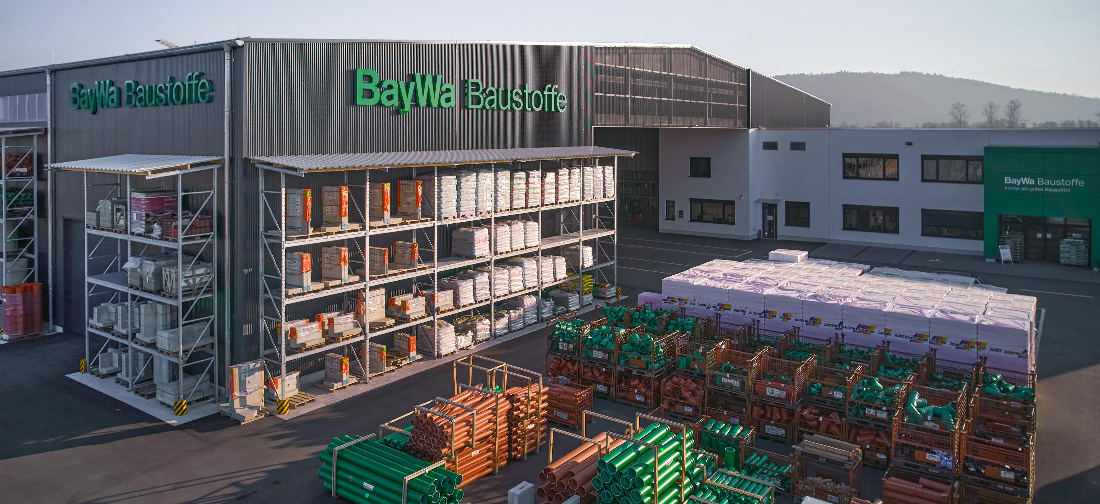 Aussenansicht eines BayWa Baustoffhofes mit Baumaterialien in Regalen und auf Paletten